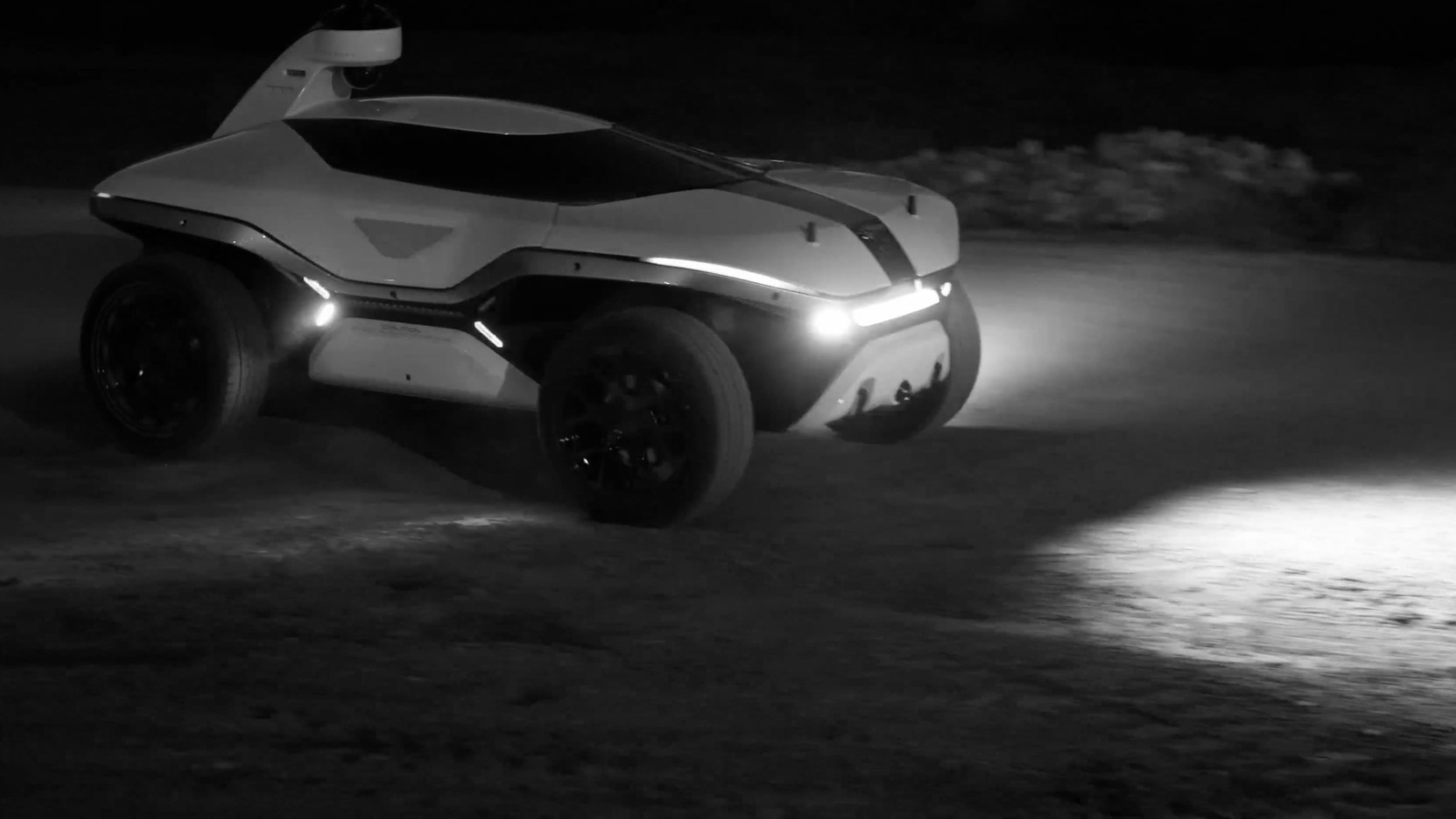 Knightscope K7 robot on rough ground at night with lights illuminated.