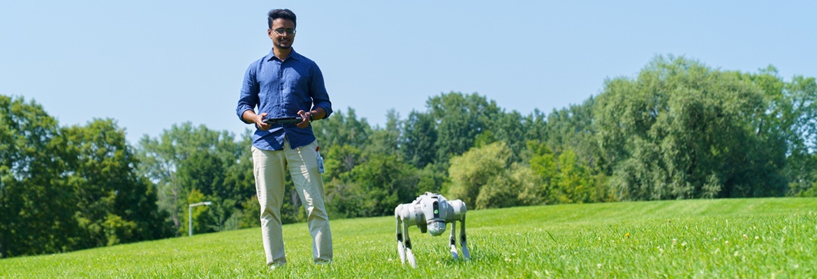 NRC source photograph of Abhishek Naik guiding Rocky outdoors with a handheld controller. The article preserves that current guidance and the research status.